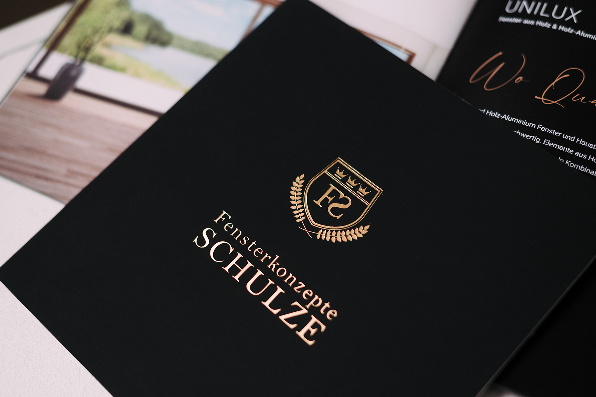 Auf dem Titel einer Imagebroschüre ist das Logo in gold heißfoliengeprägt auf schwarzem Untergrund.