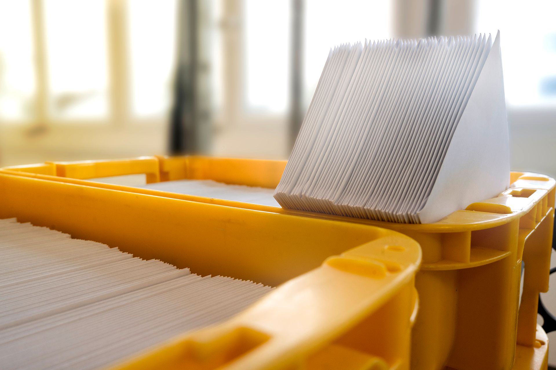 Zwei gelbe Kisten mit ordentlich gestapelten weißen Briefumschlägen, bereit zum Versand.