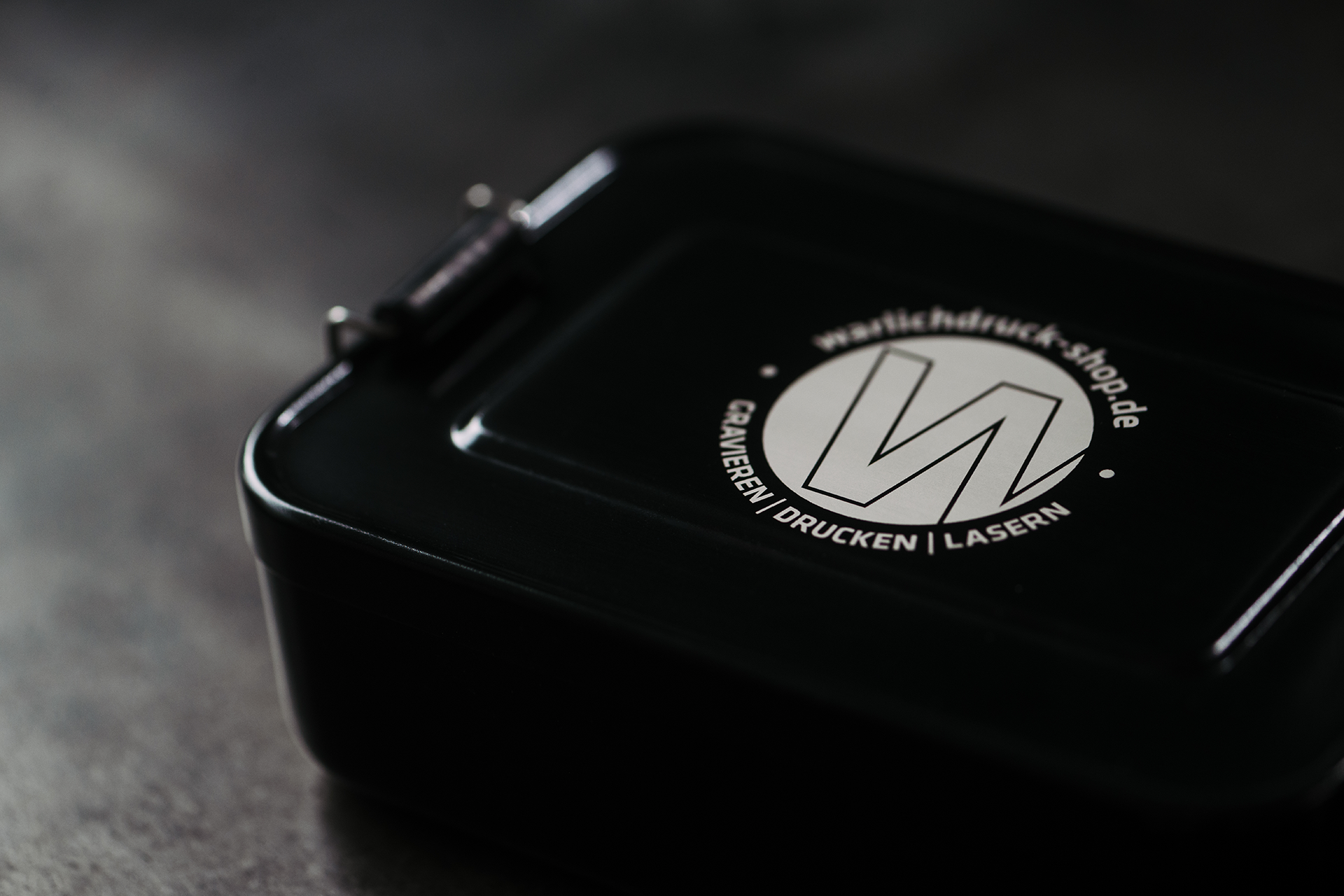 Schwarze Brotdose mit silberfarbenen Gravur.