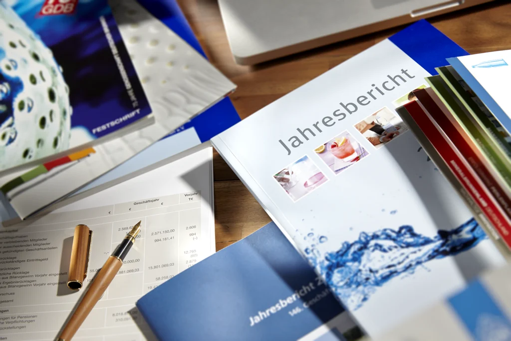 Gedruckte Jahresberichte und Geschäftsunterlagen auf einem Schreibtisch mit Füller