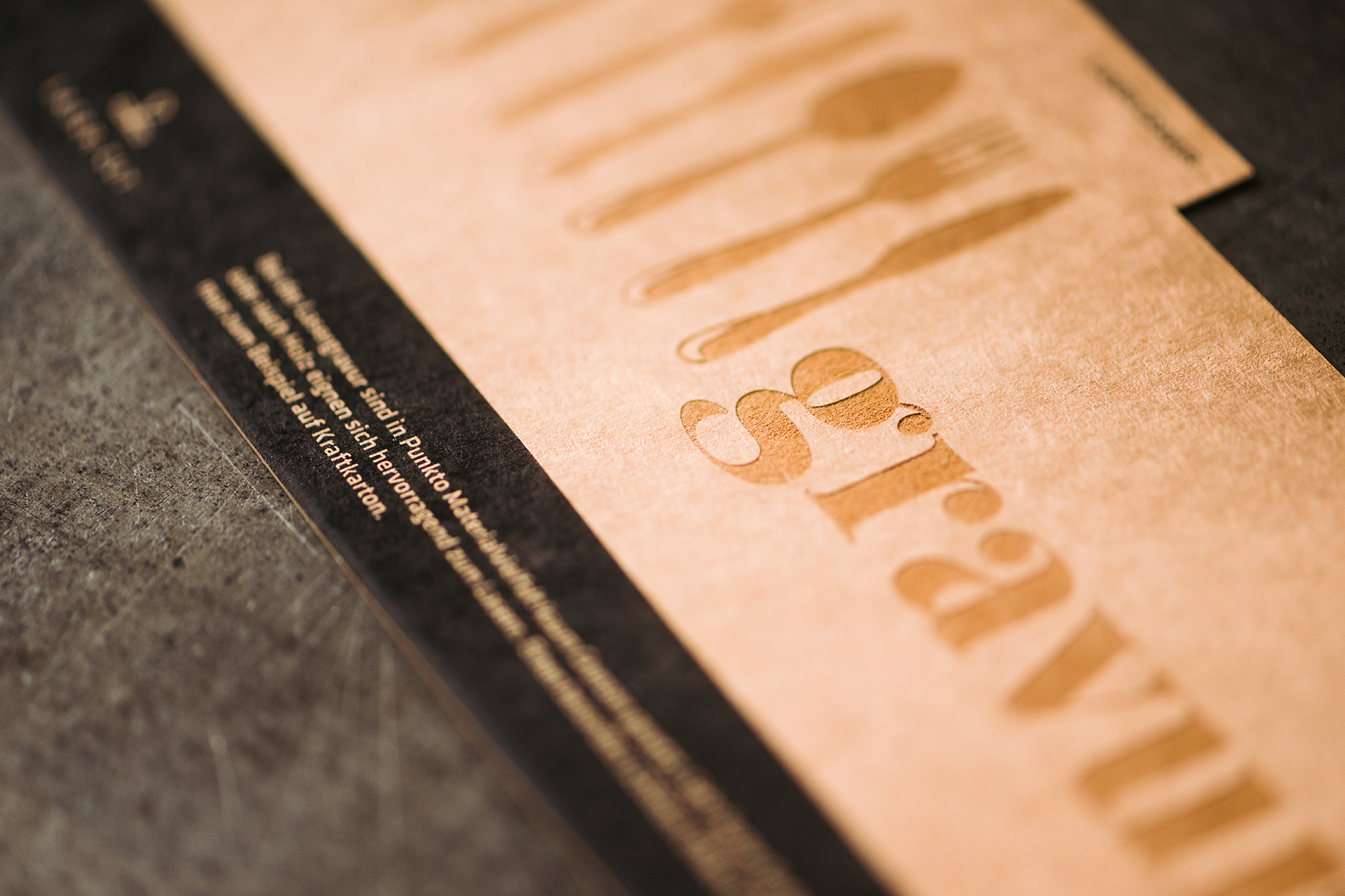 Menükarte mit Lasergravur von Besteck und Schriftzug auf braunem Naturpapier.