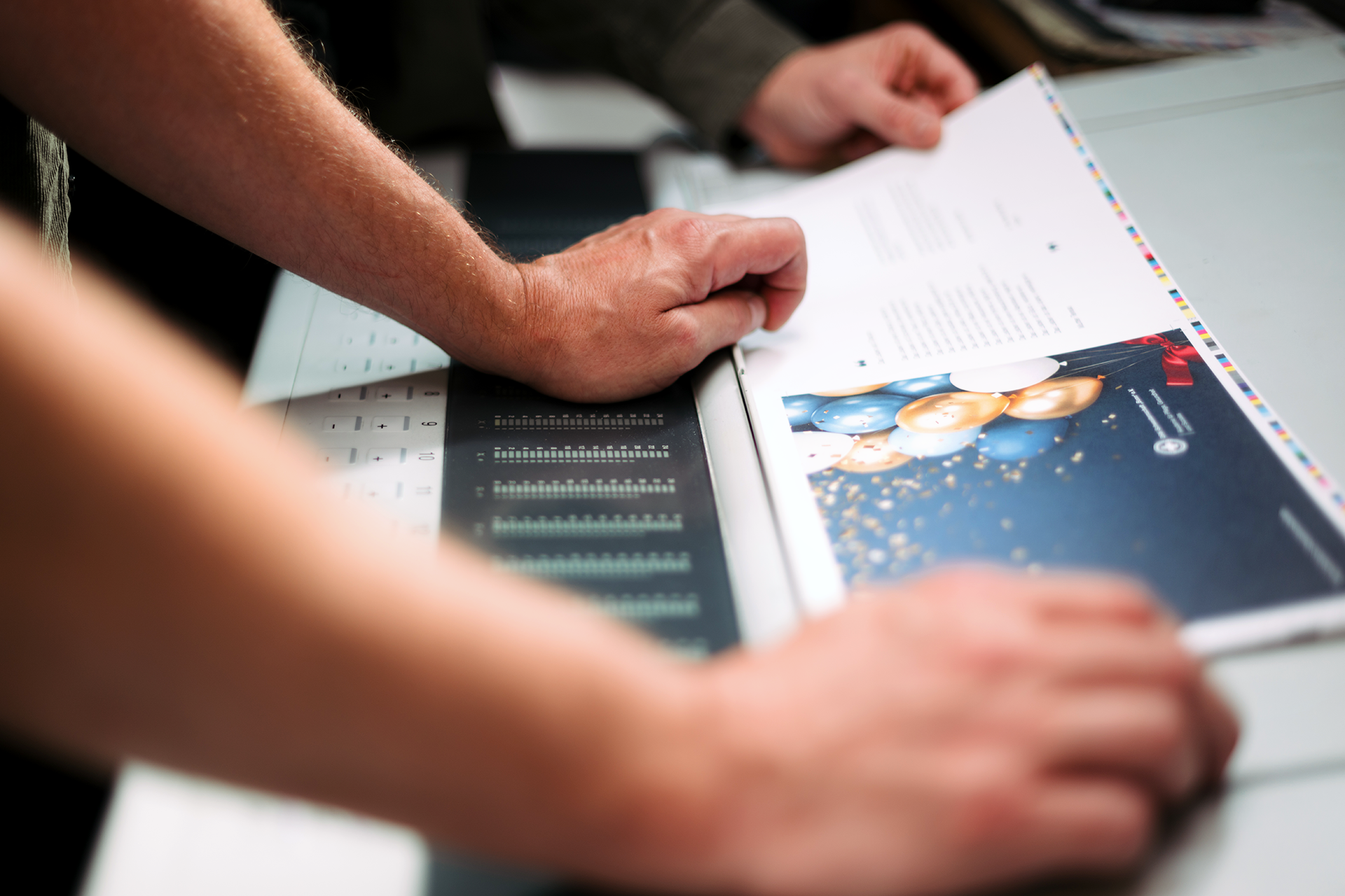 Zwei Kollegen sehen sich einen Andruck an der Druckmaschine an.