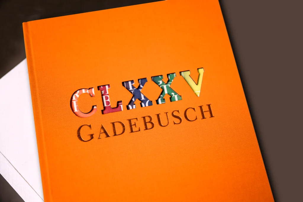 Orangefarbenes Leinencover aus denen Buchstaben ausgestanzt sind.